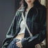 Person wearing a blue-green plaid coat with a neutral background